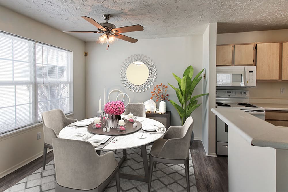 Dining area with a ceiling fan and kitchen in a model home at Westview Commons Apartments in Rochester, New York