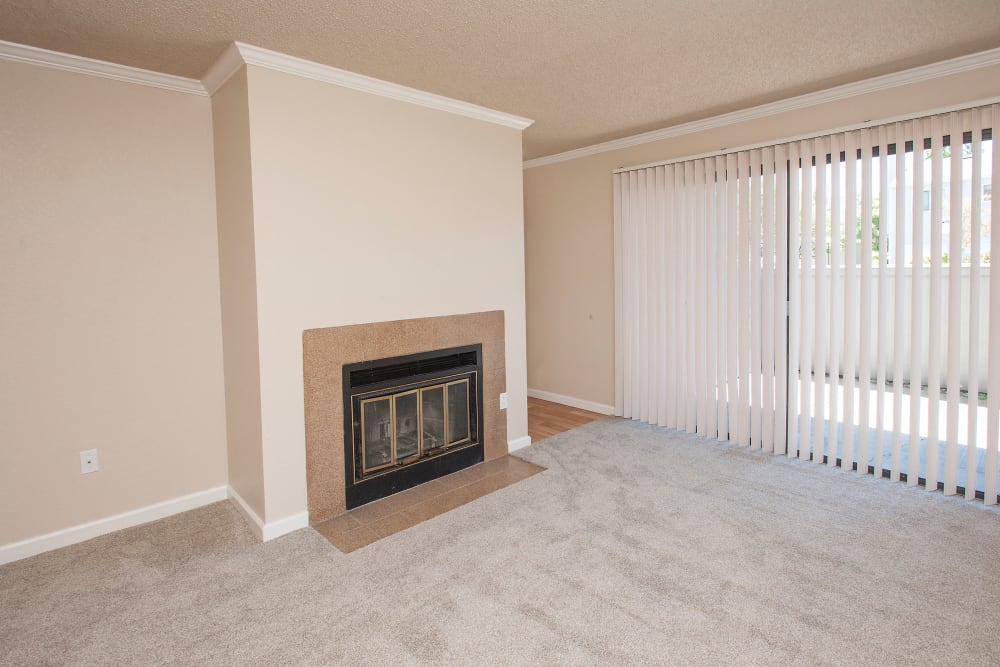 Living room with a fireplace and patio access at Plum Tree Apartment Homes in Martinez, California