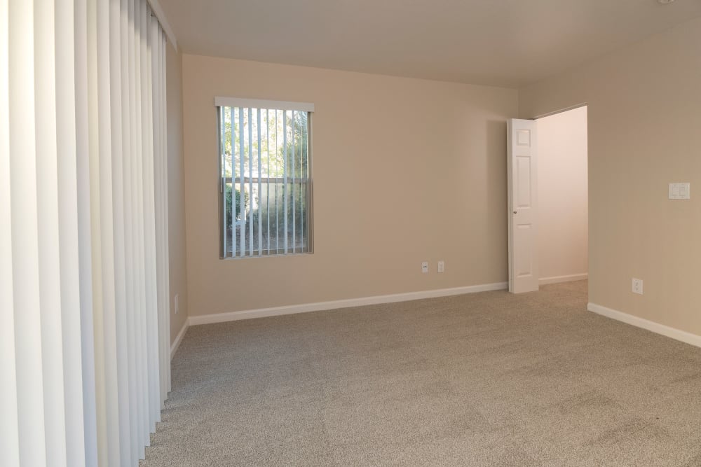 Bedroom with a large window and plush carpeting at Sterling Heights Apartment Homes in Benicia, California