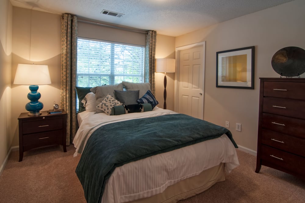 Well-furnished master bedroom with plush carpeting in a model home at Bellingham Apartment Homes in Marietta, Georgia