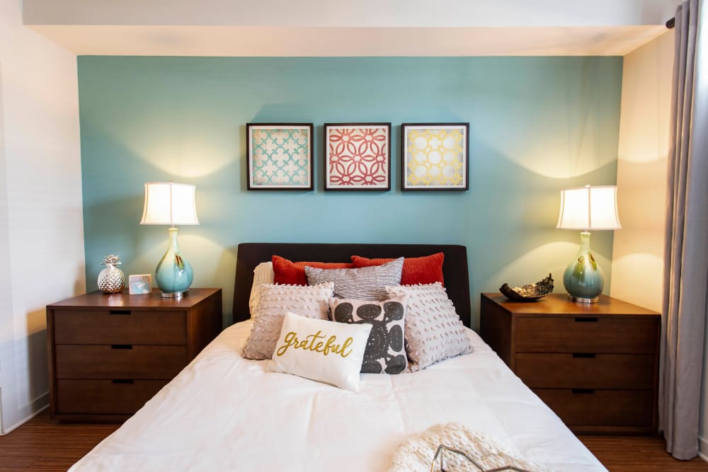 Well-furnished model home's master bedroom with an accent wall at Olympus Midtown in Nashville, Tennessee