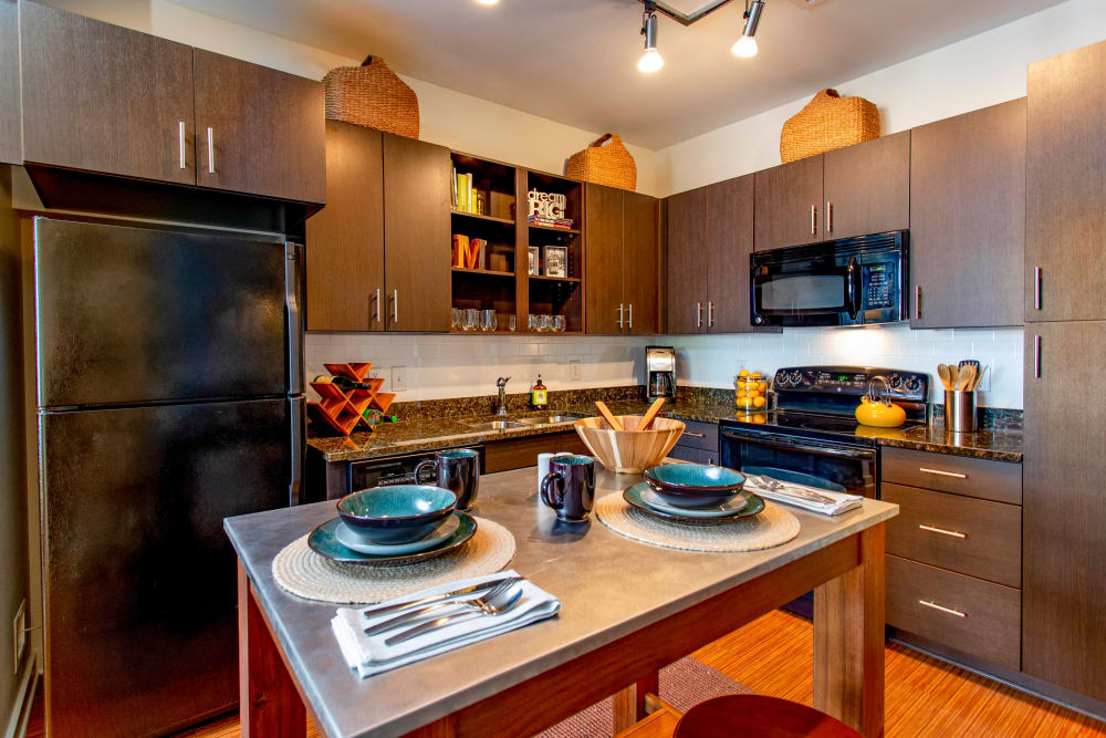 Gourmet kitchen with an island and rich wood cabinetry in a model home at Olympus Midtown in Nashville, Tennessee