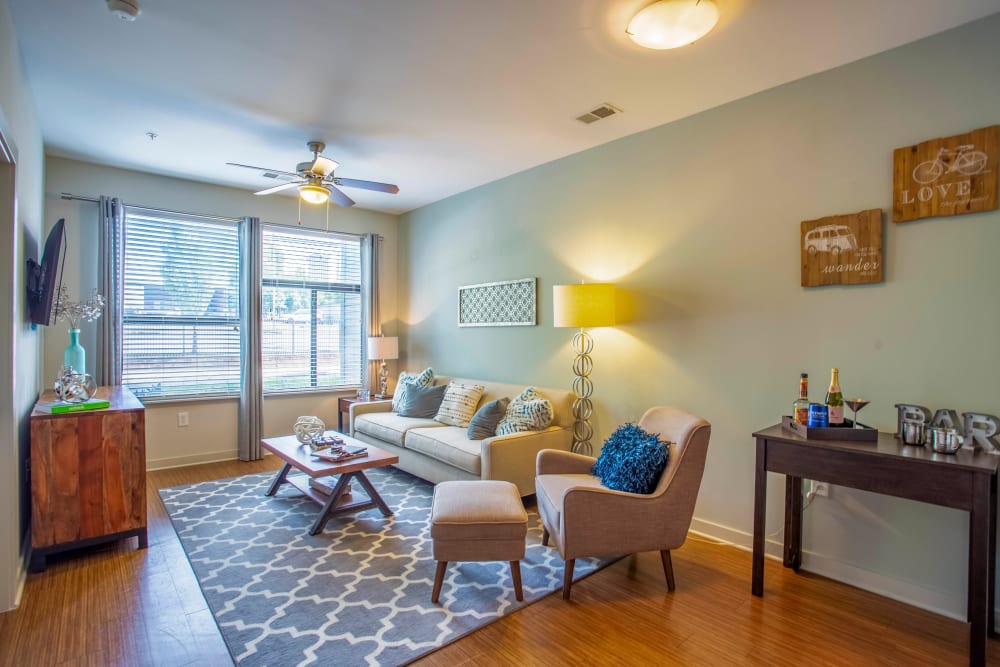 Large bay windows and a ceiling fan in a model apartment's living area at Olympus Midtown in Nashville, Tennessee