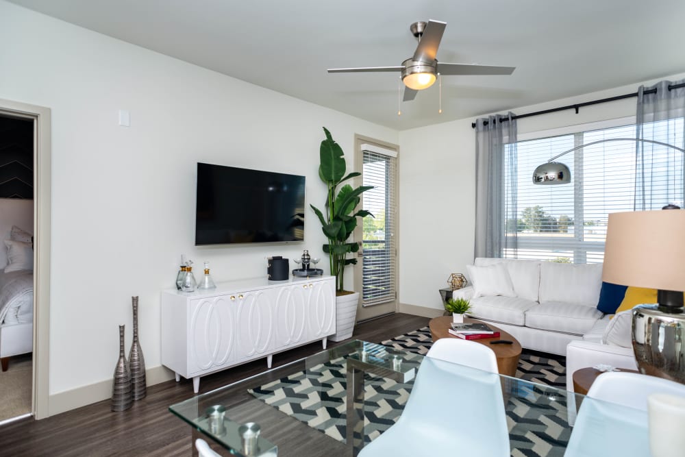 Large bay windows and a ceiling fan in the living area of a model apartment at Fusion Apartments in Irvine, California