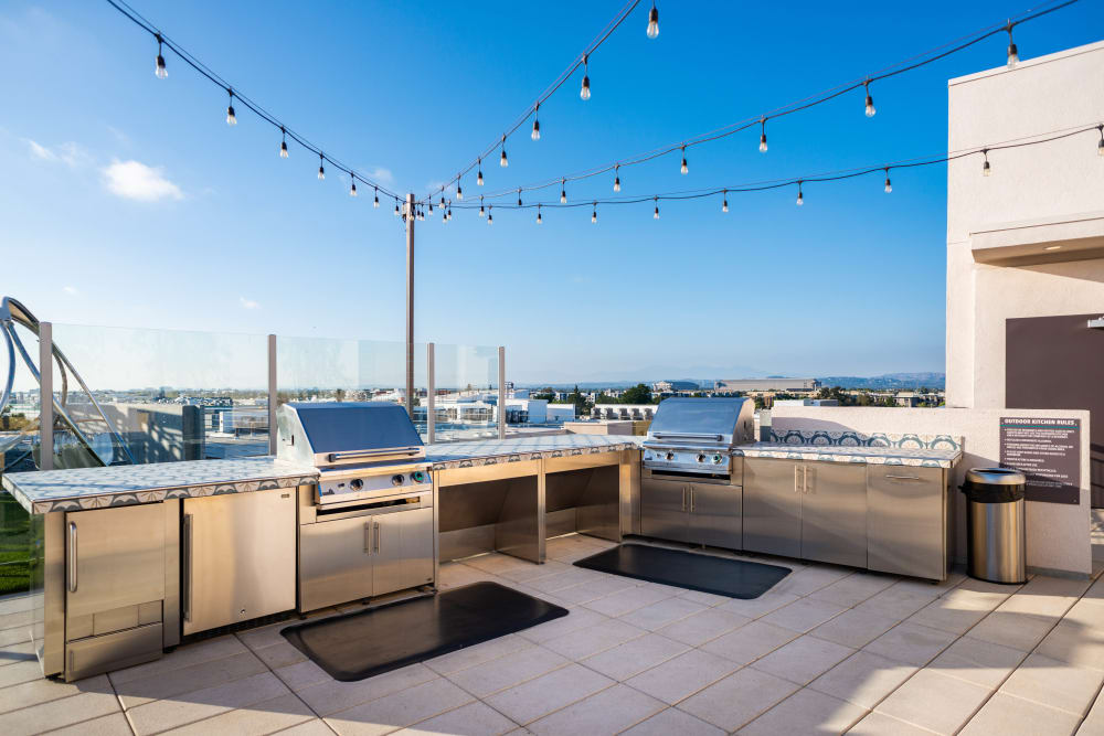 Rooftop barbecue area with gas grills at Fusion Apartments in Irvine, California
