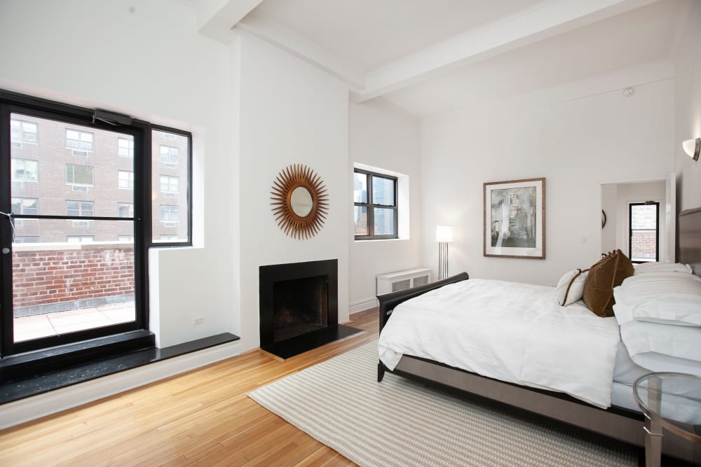Large main bedroom with a fireplace and balcony at The Sutton Collection in New York, New York