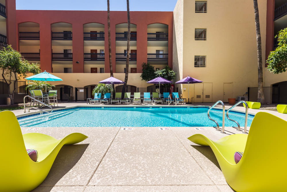 Building exterior and community swimming pool with brightly colored lounge chairs at 4127 Arcadia in Phoenix, Arizona