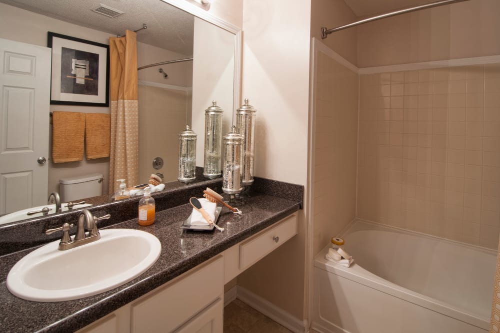 Bathroom vanity with large mirror and shower bathtub bathroom at Bellingham Apartment Homes in Marietta, Georgia