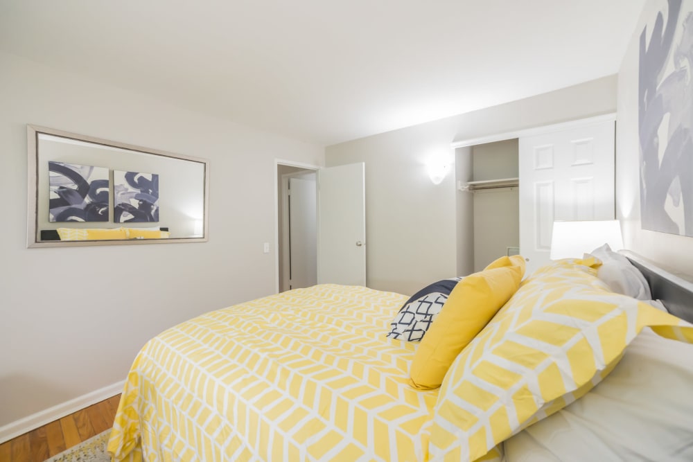 Well that bedroom features queen size bed with yellow comforter and art on the walls in an apartment at Cherokee Apartments in Philadelphia, Pennsylvania