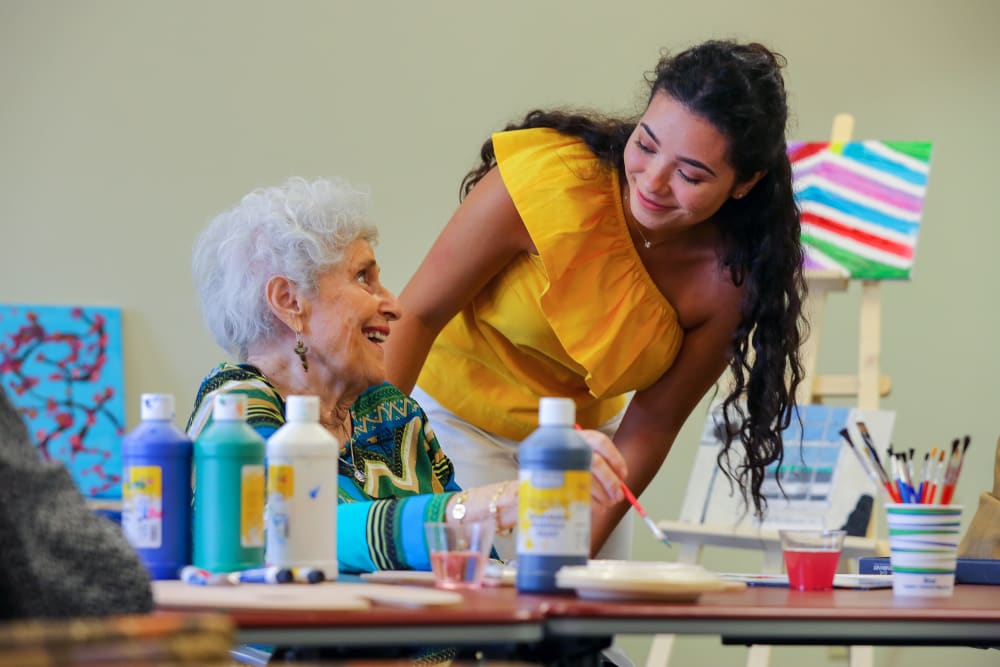 A caretaker assisting a resident with a painting activity at Harmony at Waldorf in Waldorf, Maryland
