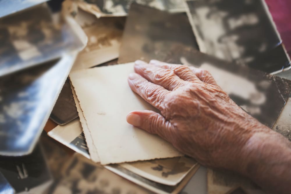 A resident's hand and collection of old photographs at Westminster Memory Care in Aiken, South Carolina