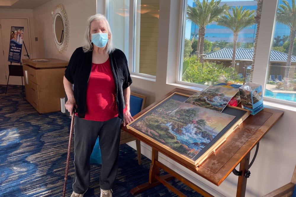 Resident standing next to a pinting in a mask at Clearwater Living