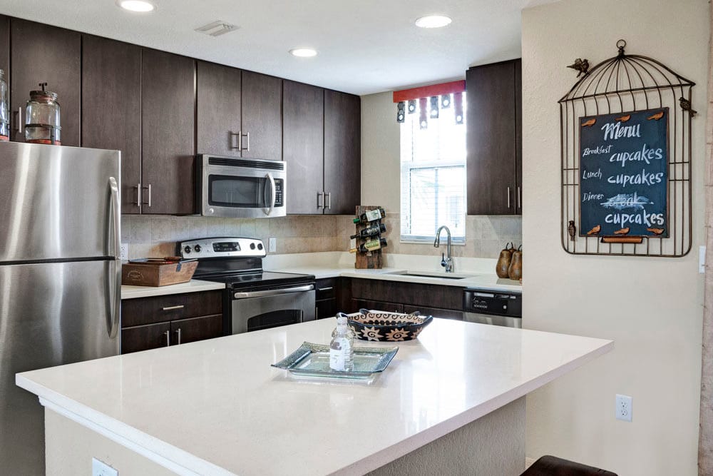 A kitchen island and stainless steel appliances are features of this kitchen in an apartment at City Center on 7th Apartment Homes in Pembroke Pines, Florida