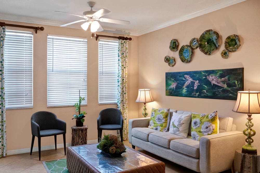 Living room with art on the walls, ceiling fan, couch and chairs at City Center on 7th Apartment Homes in Pembroke Pines, Florida