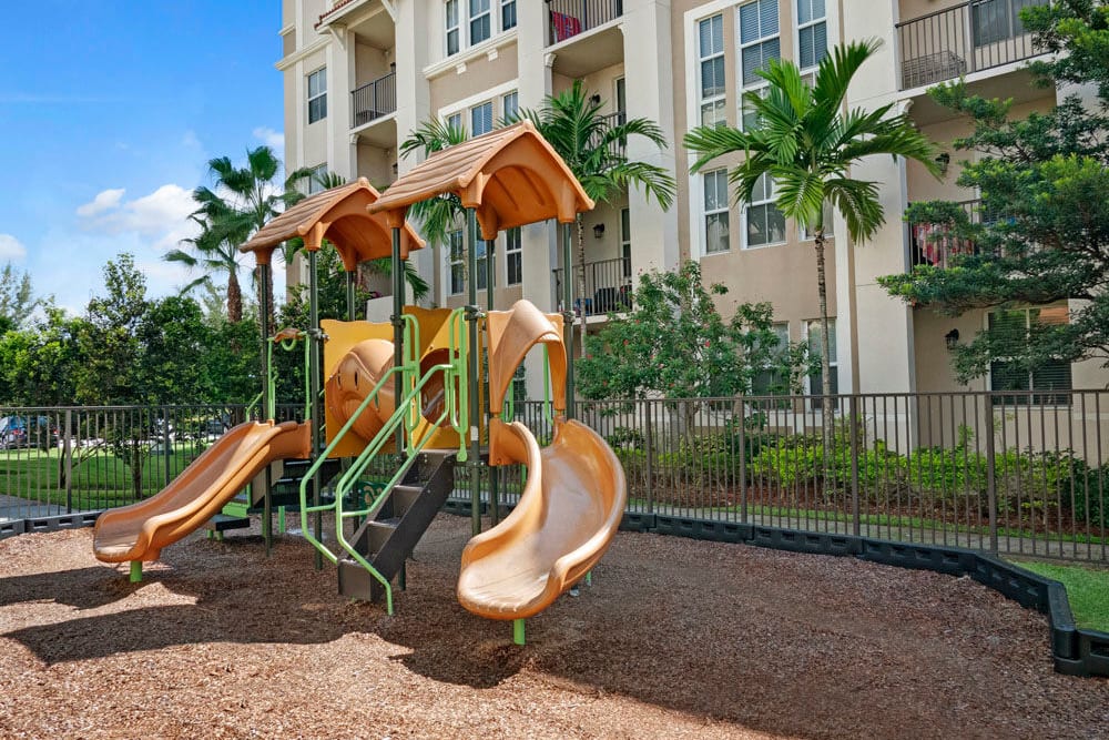 Playground equipment with apartment building in the background at City Center on 7th Apartment Homes in Pembroke Pines, Florida