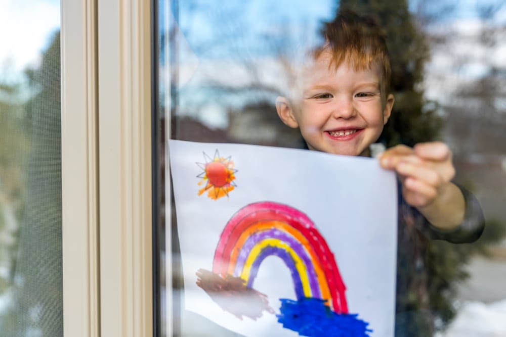 Happy child proudly taping his painting to the window of their home at Alturas Embry Hills in Doraville, Georgia