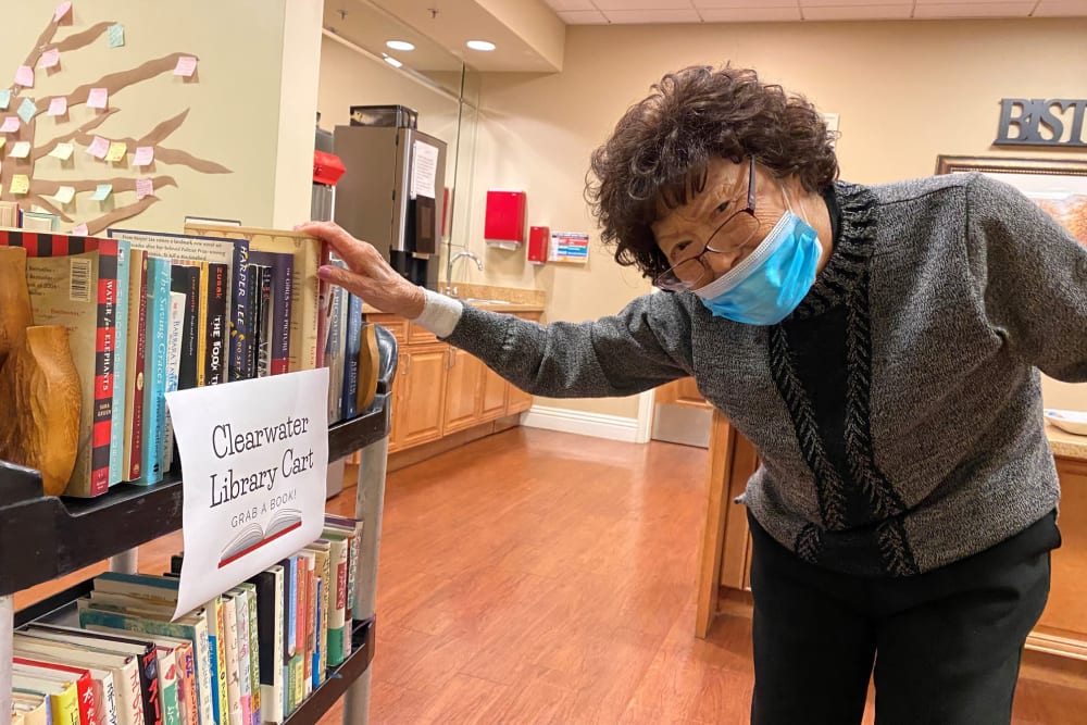 Resident picking a book from the library cart at Clearwater at South Bay
