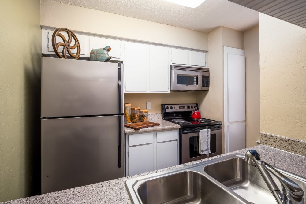 Kitchen with stainless steel appliances and granite countertops at The Fairway Apartments in Plano, Texas