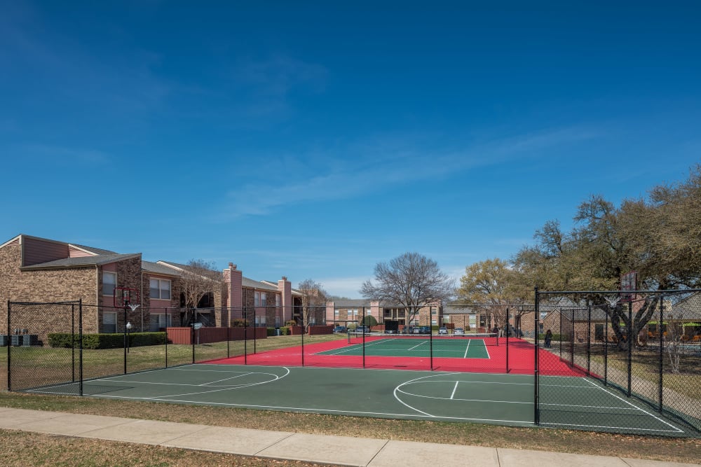 Basketball court with adjacent tennis court on site at The Fairway Apartments in Plano, Texas