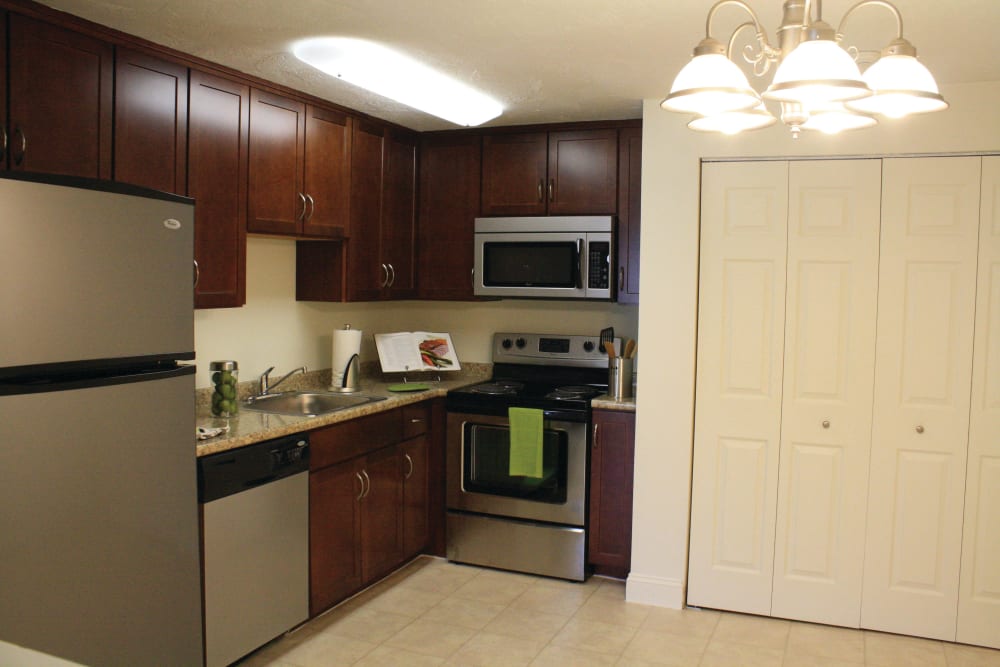 Kitchen with stainless steel appliances and cherry wood cabinets at The Village at Marshfield in Marshfield, Massachusetts