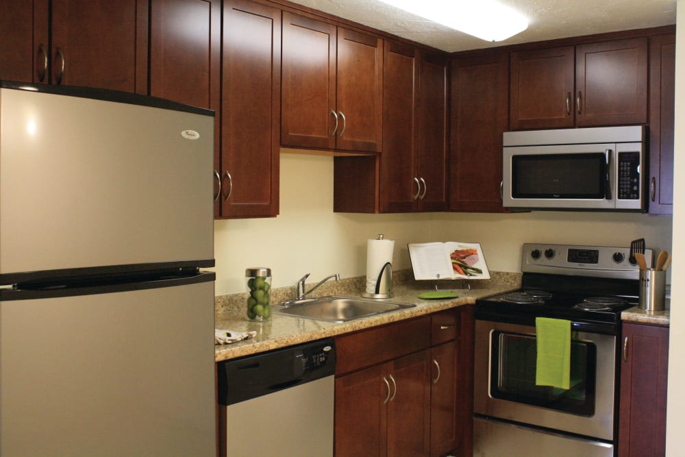 Kitchen with stainless steel appliances and cherry wood cabinets at The Village at Marshfield in Marshfield, Massachusetts
