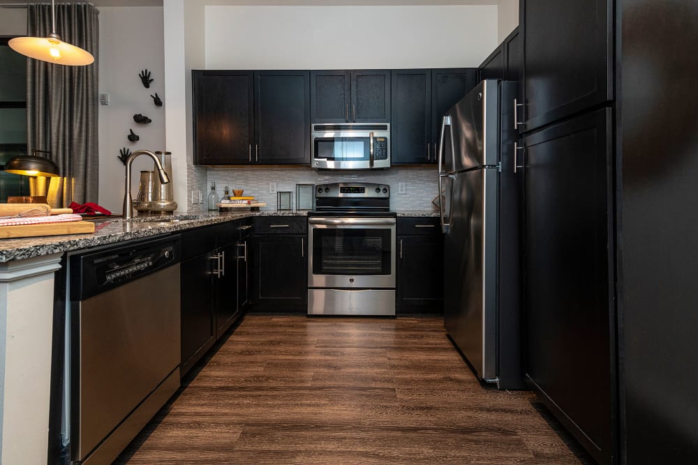 Rich dark wood cabinetry and hardwood flooring in a contemporary model home's kitchen at Twin Creeks Crossing in Allen, Texas