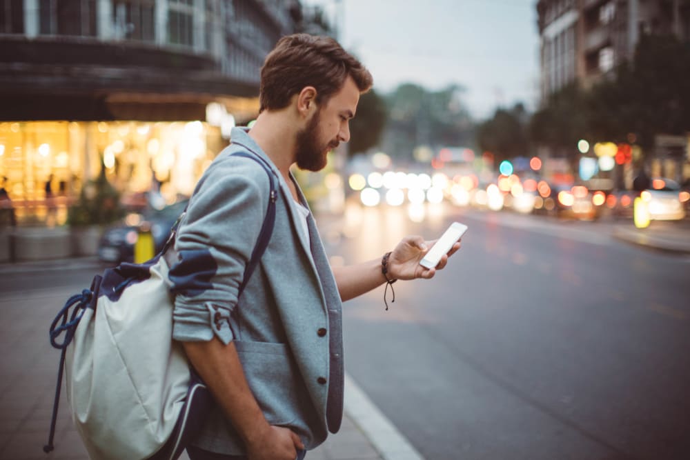 Resident checking his phone at a stoplight downtown while walking to work near Ellington Midtown in Atlanta, Georgia