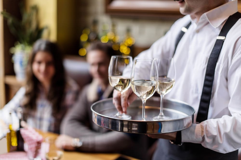 Server delivering glasses of wine to a group of resident friends at a restaurant near Ellington Midtown in Atlanta, Georgia