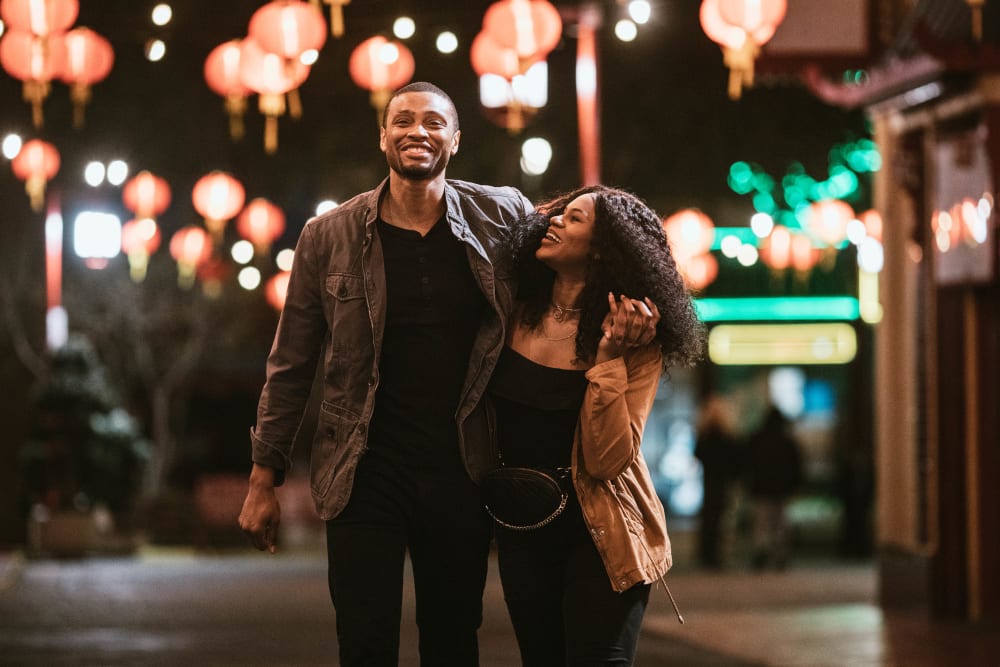 Couple with their arms around each other while walking downtown in the evening near Ellington Midtown in Atlanta, Georgia