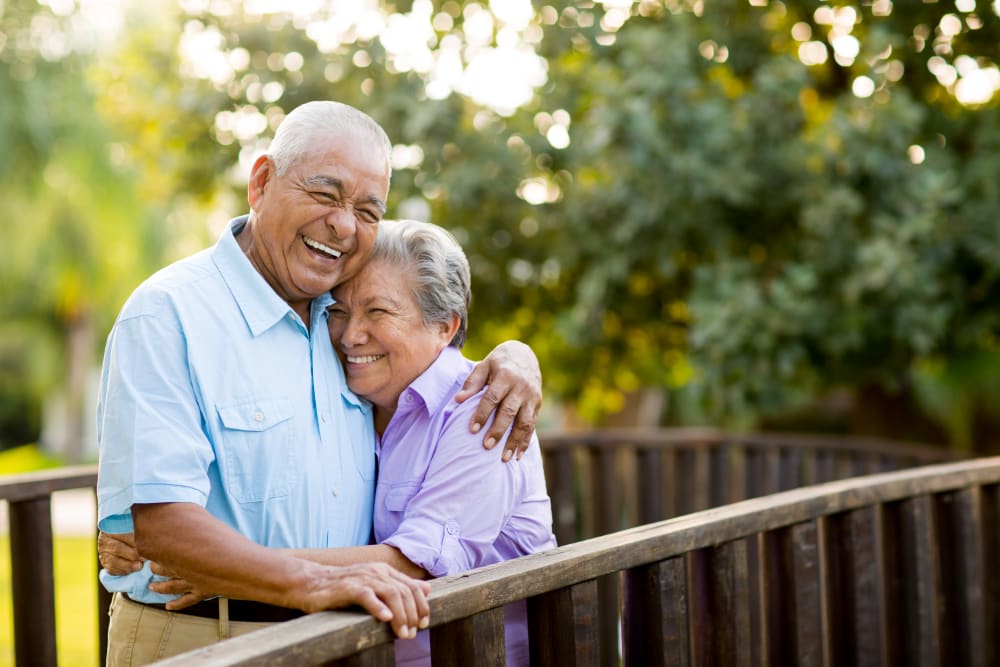 Resident couple hugging on a bridge outside near Edencrest at Tuscany in Altoona, Iowa