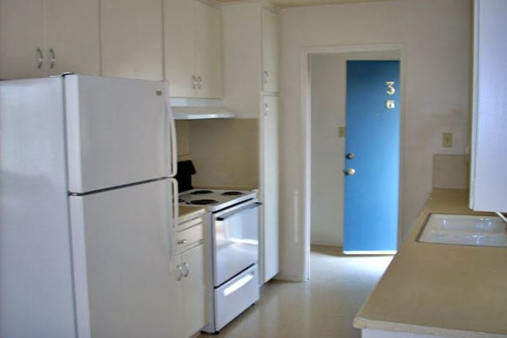 Kitchen with white wood cabinets and white appliances at Highland View Court in Bakersfield, California