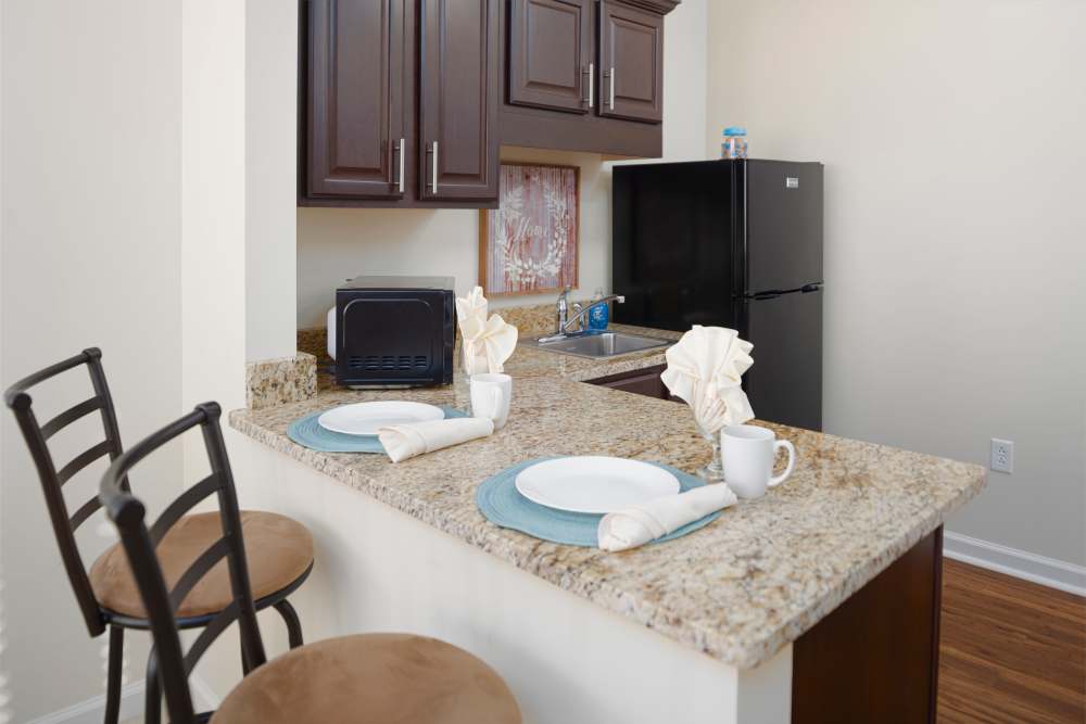 Apartment kitchen with patterned marble countertop and dark brown cabinetry at Harmony at Spring Hill in Lorton,Virginia