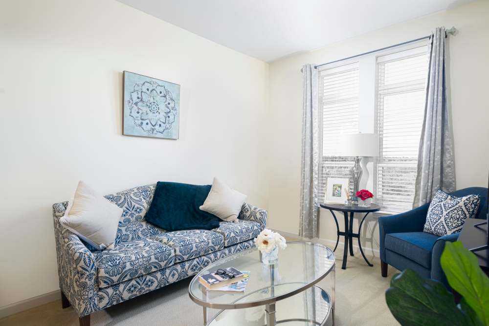 Bright apartment room with sofa set and a large window with blinds at Harmony at Spring Hill in Lorton,Virginia
