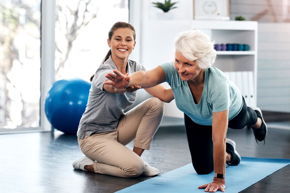 Caregiver assisting a resident who is doing yoga at a Jaybird Senior Living community 