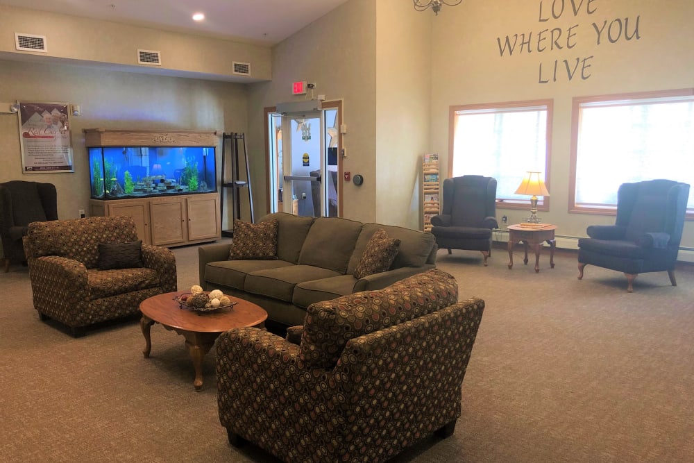 Large lounge with a bright fish tank in it at Arlington Place Oelwein in Oelwein, Iowa