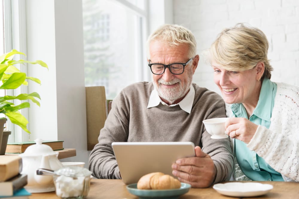 Resident couple using a tablet while eating breakfast at Edencrest at Siena Hills in Ankeny, Iowa