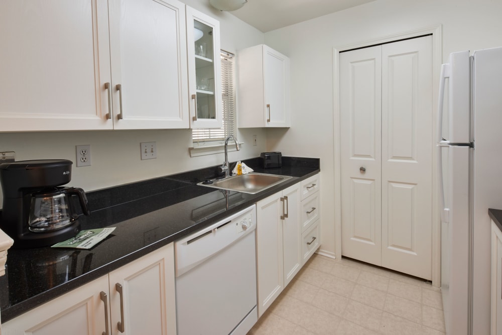 Model kitchen with black countertops and white wood cabinets at Citation Club in Farmington Hills, Michigan