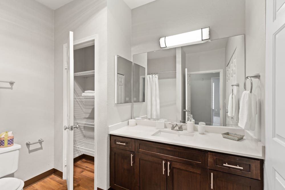 Master bathroom with brown cabinetry and a linen closet at Wildreed Apartments in Everett, Washington