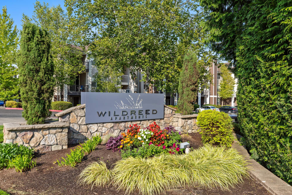 Monument sign surrounded by beautiful landscaping at Wildreed Apartments in Everett, Washington
