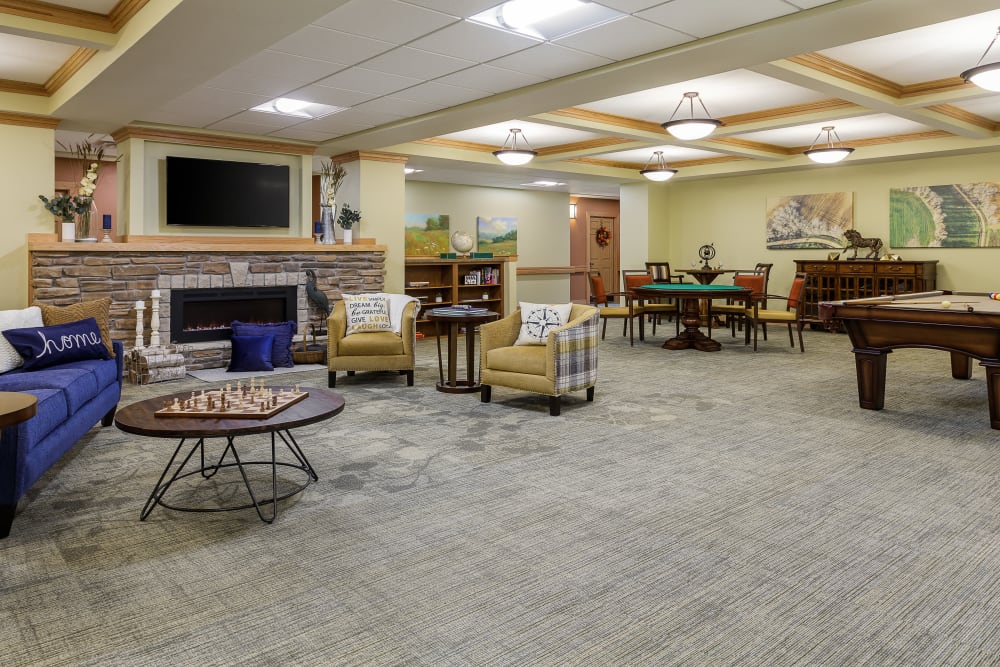 Resident lounge with lots of space, a tv, and a fireplace at Edencrest at Beaverdale in Des Moines, Iowa
