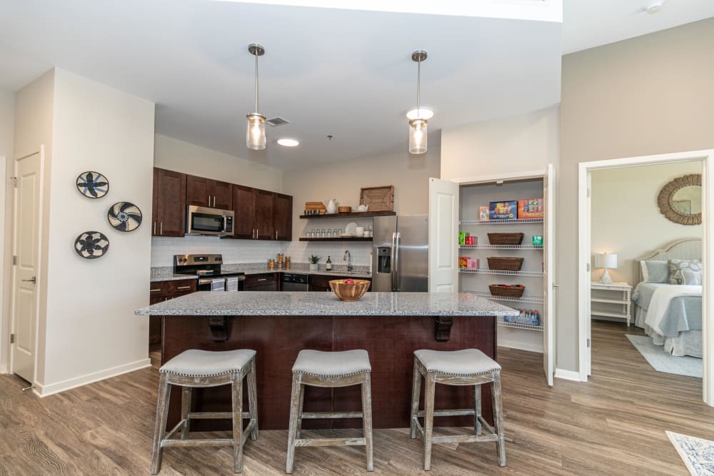 Model home's gourmet kitchen with granite countertops, an island with bar seating, and dark wood cabinetry at The Station at River Crossing in Macon, Georgia