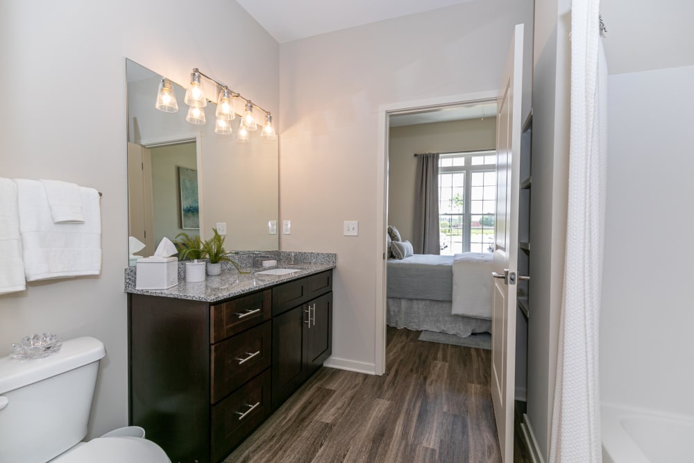 En suite primary bathroom with hardwood floors and a large vanity mirror in a model home at The Station at River Crossing in Macon, Georgia