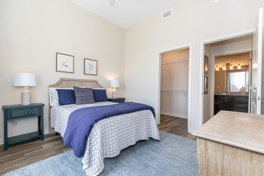 Primary bedroom with a walk-in closet and en suite bathroom in a model apartment at The Station at River Crossing in Macon, Georgia