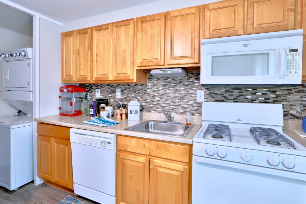 Kitchen with white appliances and tile backsplash at Gwynnbrook Townhomes in Baltimore, Maryland