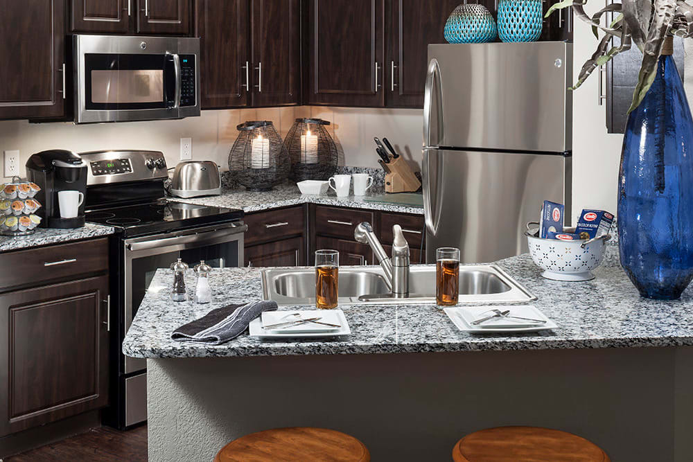 Gourmet kitchen with an island and espresso wood cabinetry in a model home at Hyde Park at Montfort in Dallas, Texas