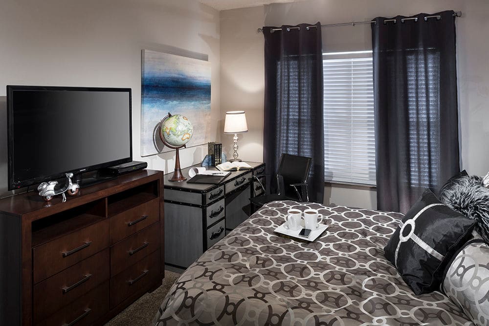 Large bay window and bold furnishings in model home's bedroom at Hyde Park at Montfort in Dallas, Texas