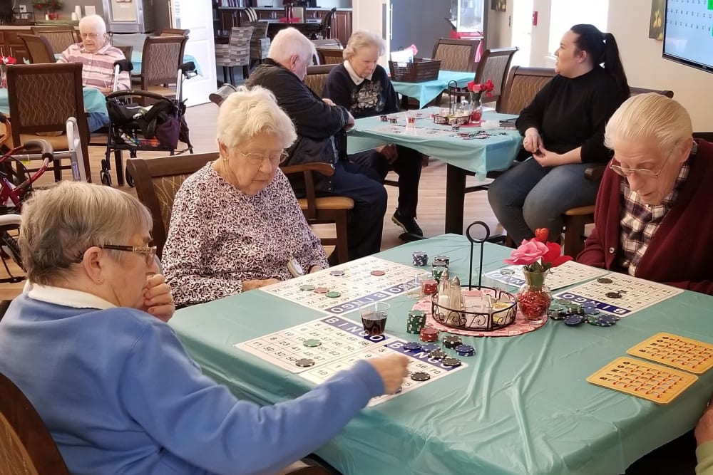 3 Residents sitting at a table in a large room playing bingo at Emery Place in Robins, Iowa