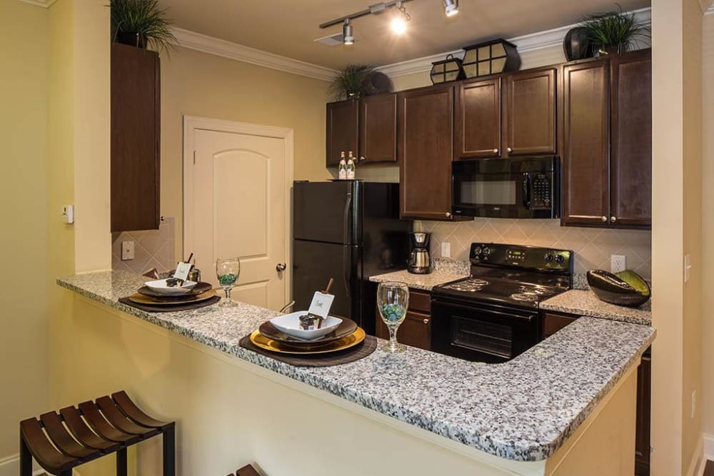 Modern kitchen with granite countertops and a breakfast bar in a model home at The Preserve at Greison Trail in Newnan, Georgia