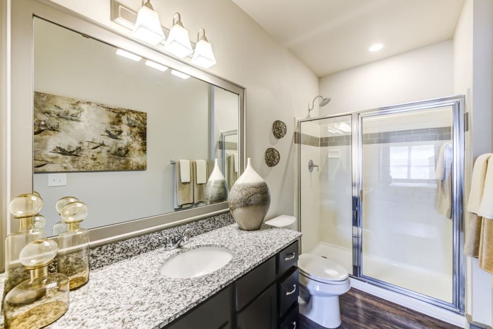 Model bathroom with granite countertops and large vanity mirror at The Sovereign in Fort Worth, Texas
