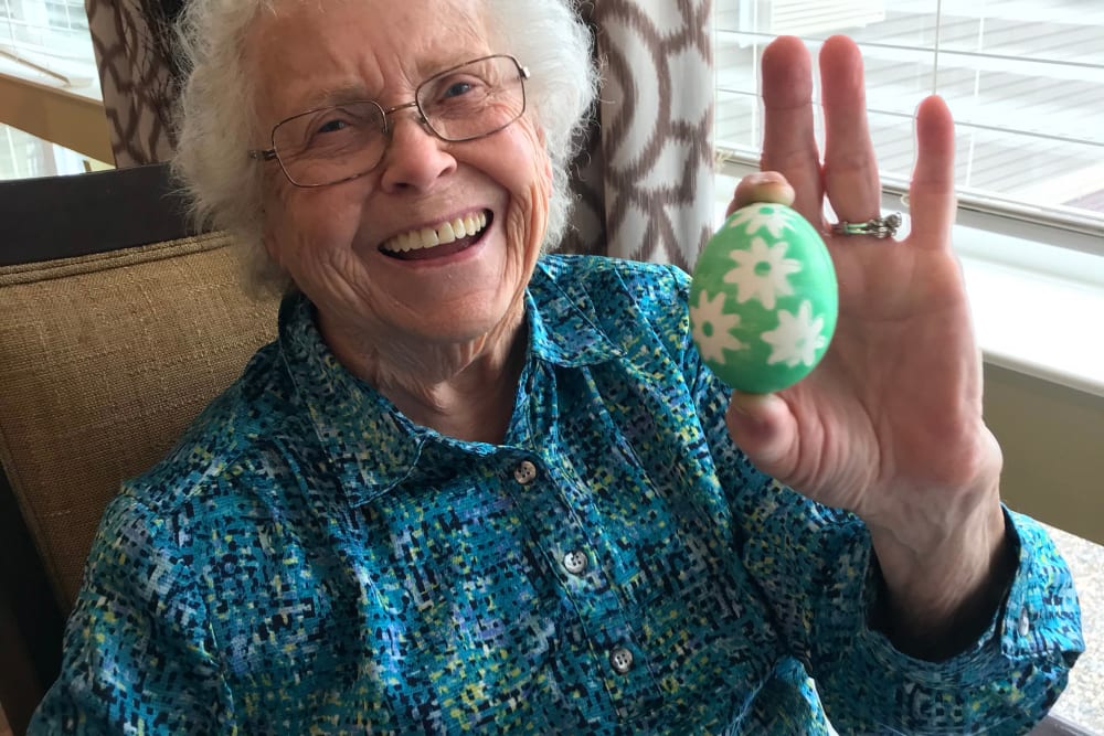 Resident smiling and showing her Easter egg at Edencrest at The Legacy in Norwalk, Iowa